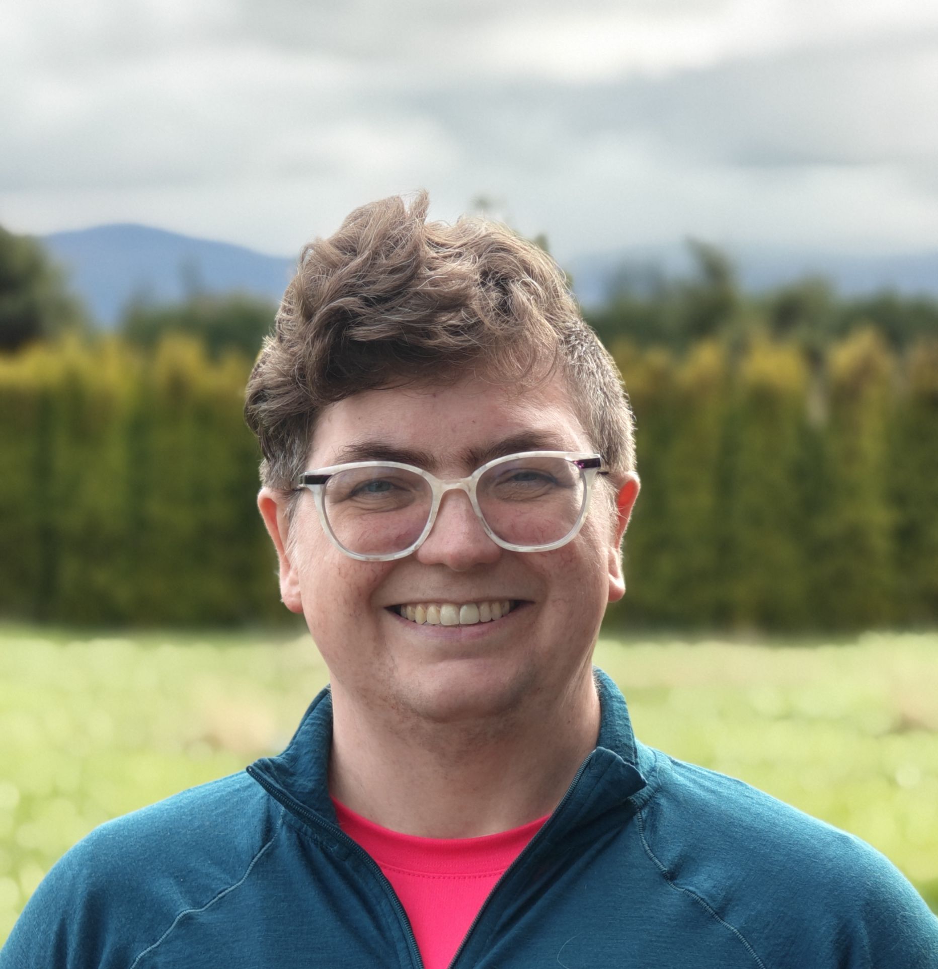 Rachel Bowen outdoors on the Olympic Peninsula with mountains and evergreens behind her